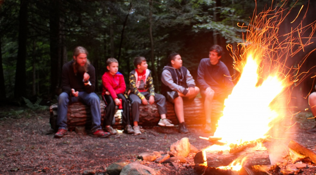 young campers and leaders sit around a campfire