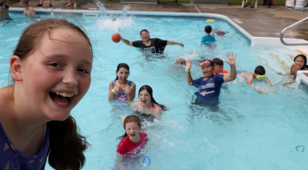 kids pose for photo while playing in a pool